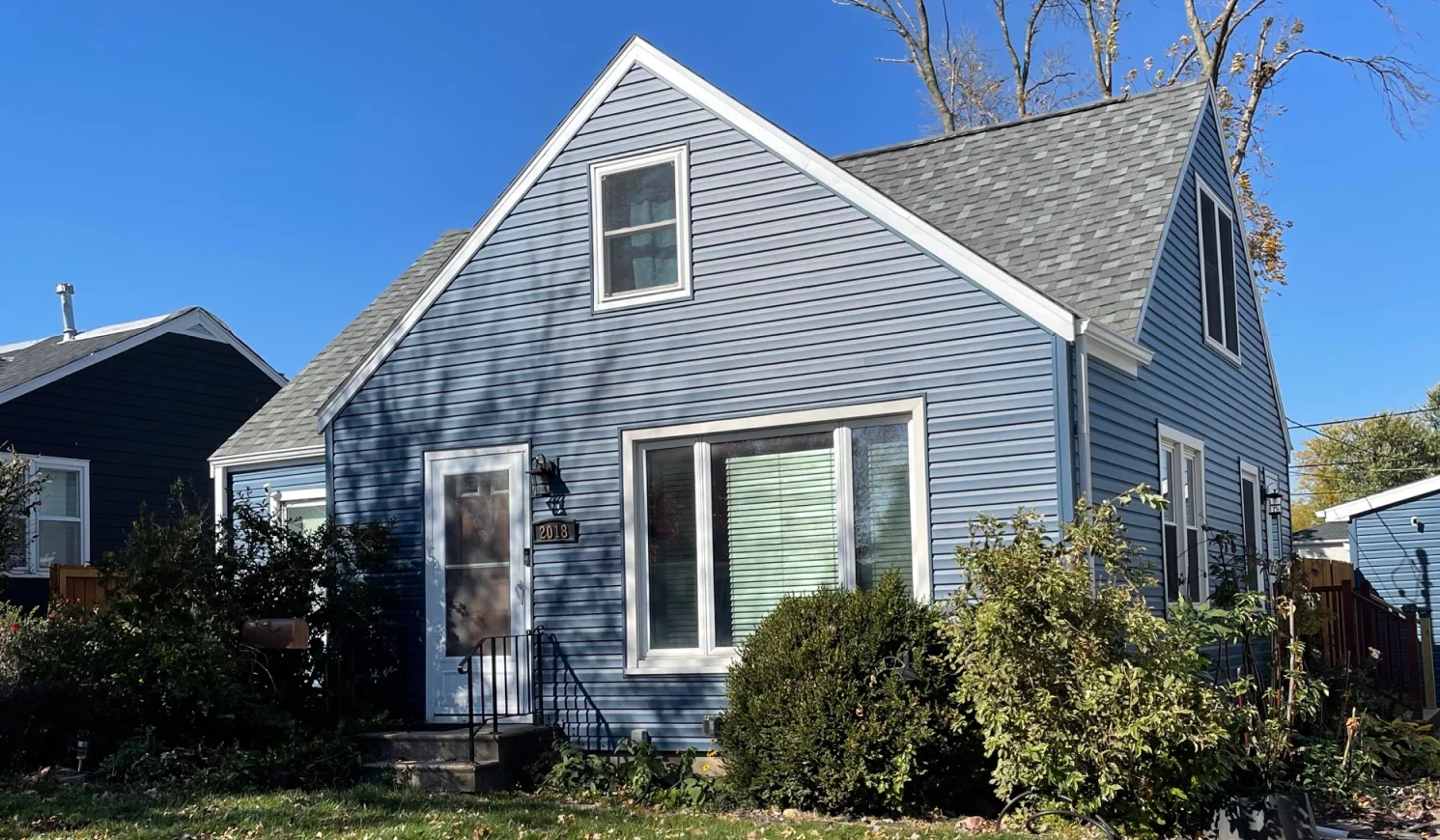 A blue house with white trim and gray roof